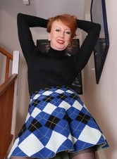 Mature redheaded woman in skirt poses on stairs showing her panties under skirt